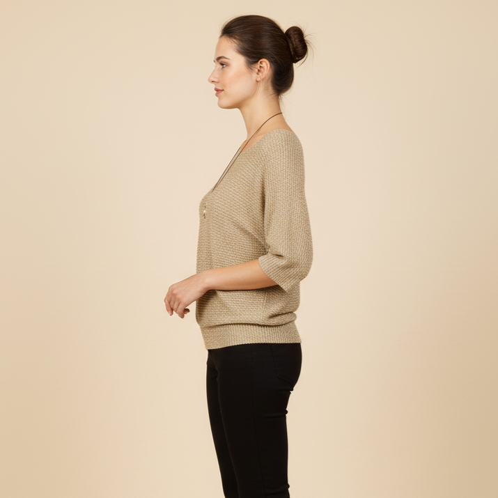 Woman wearing a beige sweater and black pants on a beige background