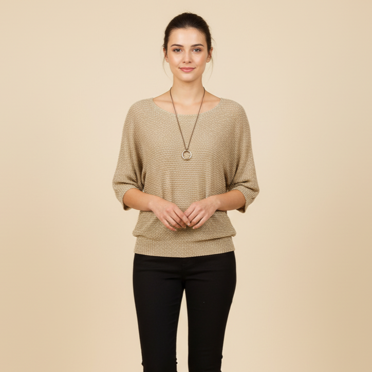 Woman wearing a beige sweater and black pants on a beige background