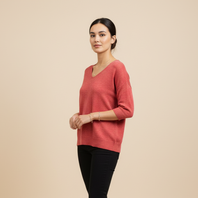 Woman wearing a pink sweater and black pants on a beige background